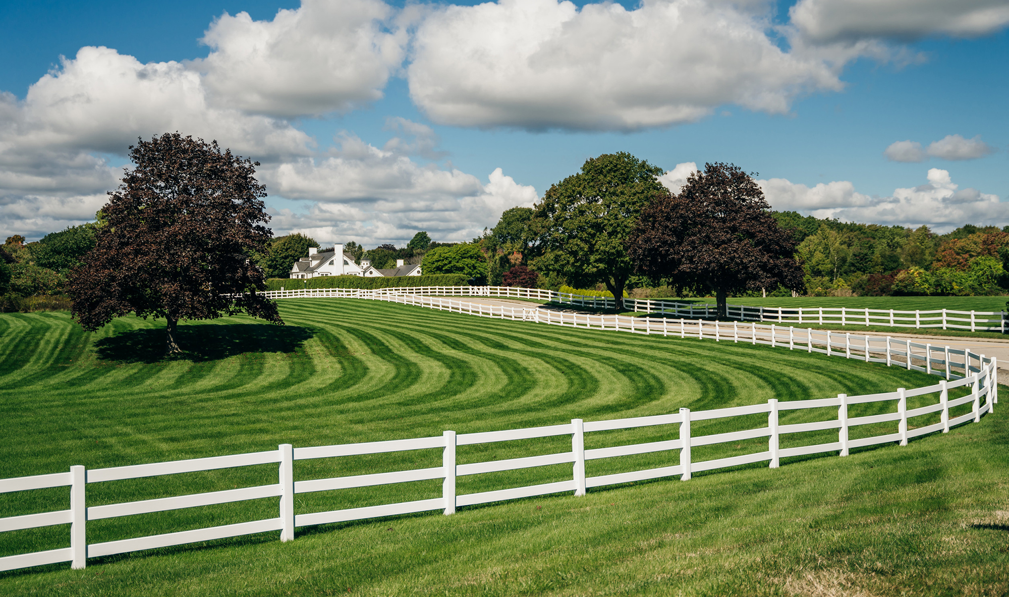 perfect american farm with a green lawn and a white fence. Farm country house in the field with fence. Countryside of Canada